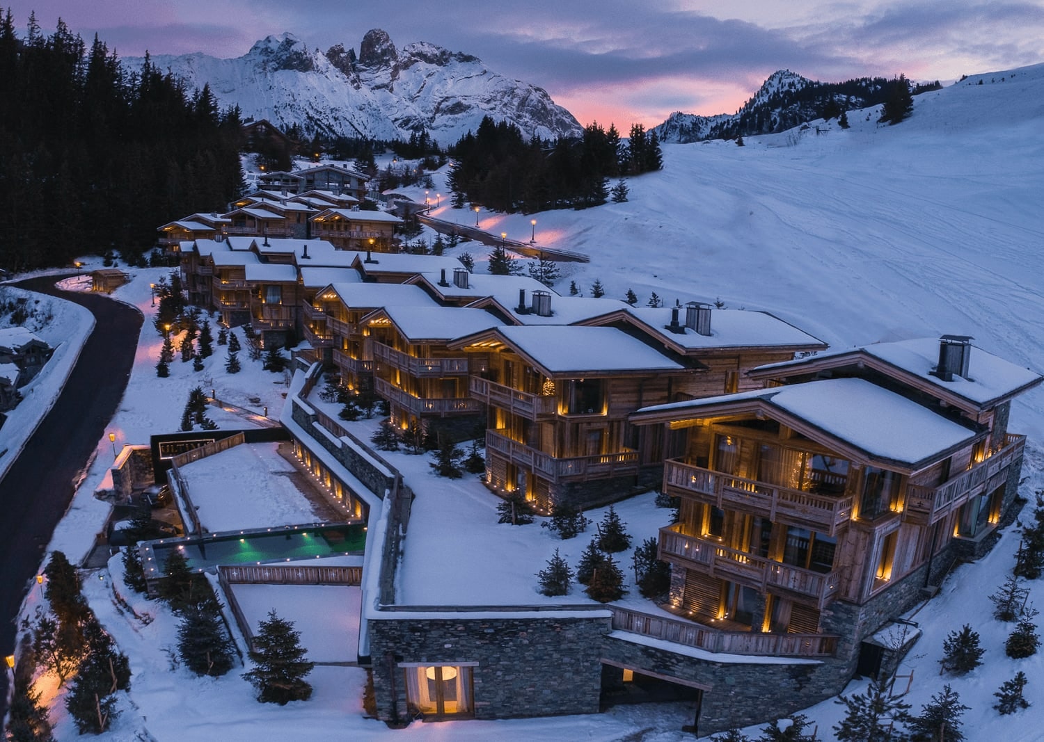 Chalet de nuit à Courchevel, éclairé et enneigé, vue imprenable sur les montagnes des Alpes.