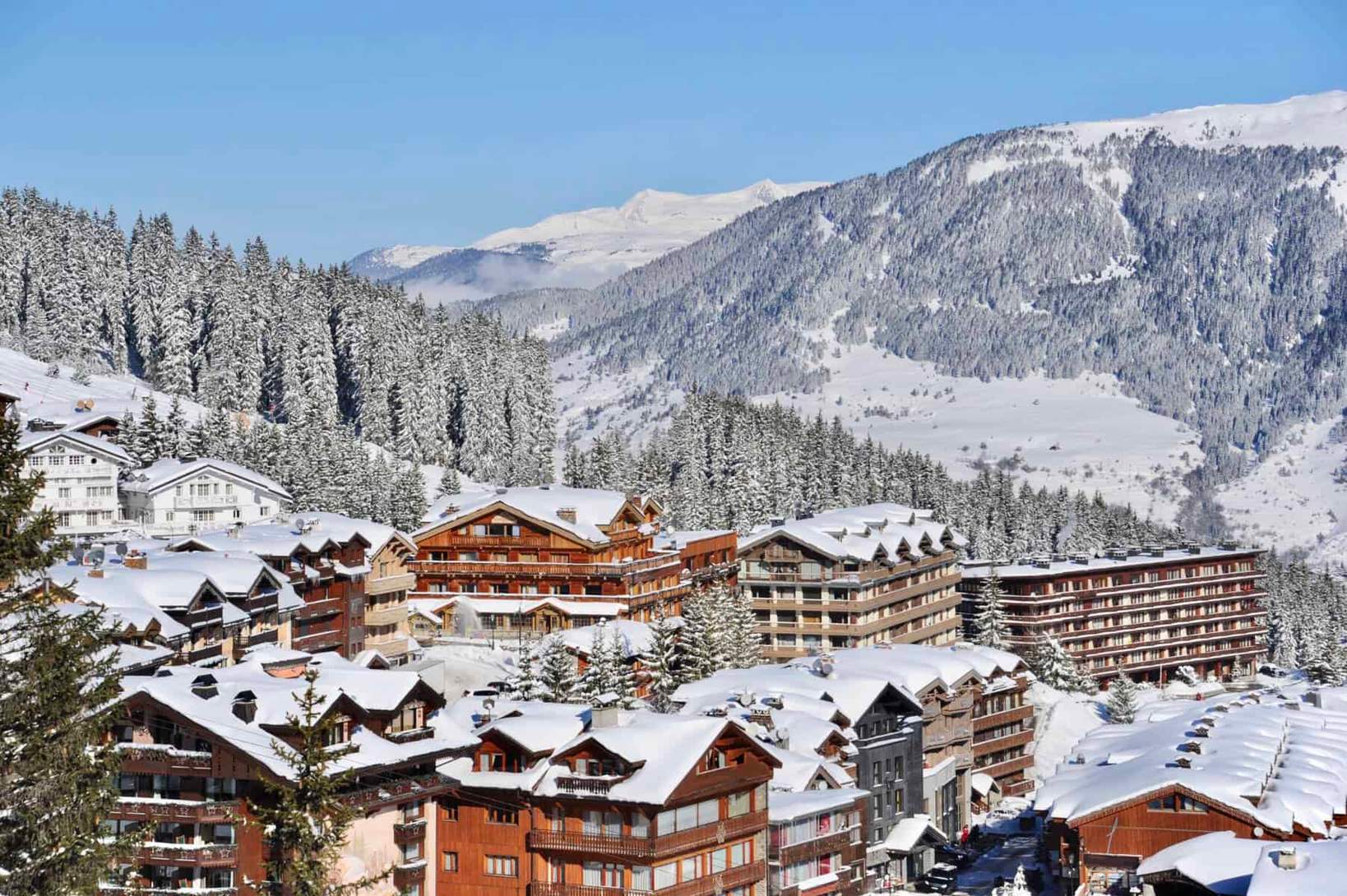 Chalet de nuit à Courchevel, éclairé et enneigé, vue imprenable sur les montagnes des Alpes.